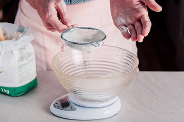 Man sifting flour for pizza dough