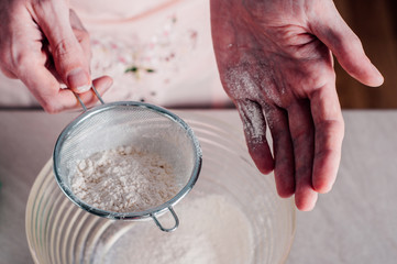 Fototapeta premium Man sifting flour for pizza dough