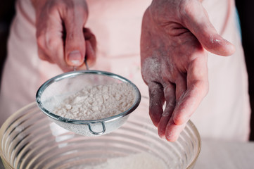 Fototapeta premium Man sifting flour for pizza dough
