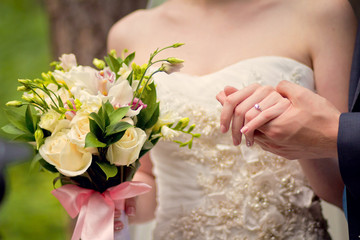 Hands of groom and bride on a wedding bouquet