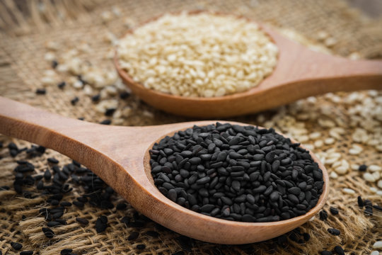 Black sesame and white sesame seed on wooden spoon
