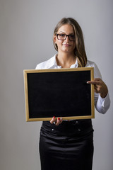 Young businesswoman pointing to blank chalkboard