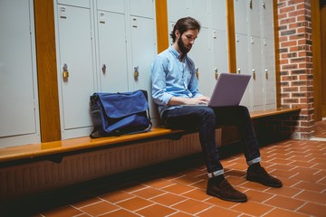 Hipster student using laptop in hallway