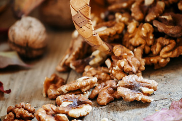 Peeled halves walnuts spill out of a wicker basket on autumn bac