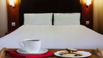 Tray with tea and biscuits with bed in background