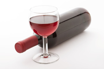 Glass and bottle of red wine unusually on white background.
