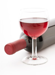 Glass and bottle of red wine unusually on white background.