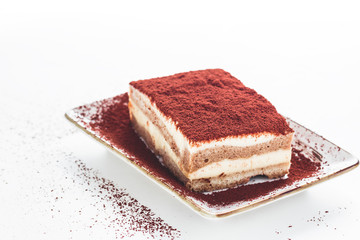 Tasty tiramisu cake with coffee beans on white