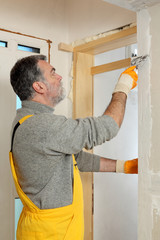 Construction site, worker installing gypsum board using trowel and plaster
