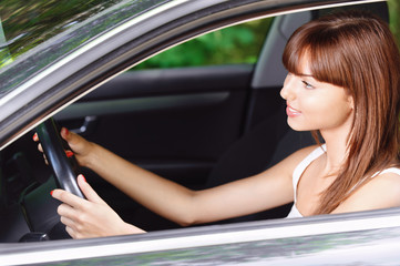 Obraz na płótnie Canvas portrait of young smiling woman driving car