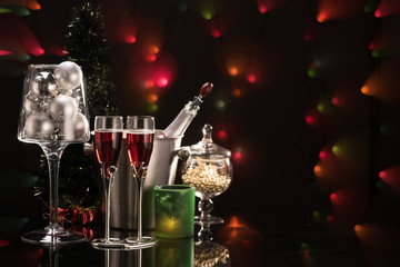 Two glasses of red champagne and Christmas decorations on colorful blurred lights background