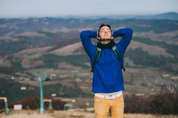 Fototapeta premium Handsome young man standing on a rock, enjoying the view