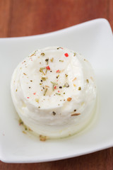 fresh cheese on white plate on brown wooden background