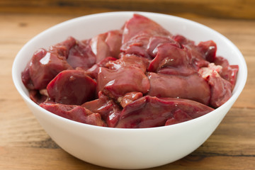 chicken liver in white bowl on brown wooden background