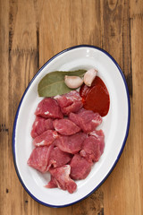 raw meat with garlic on dish on wooden background