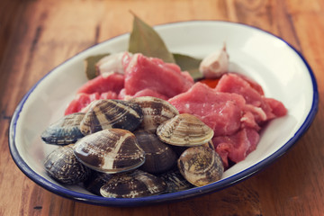 raw meat with garlic and clams on dish on brown wooden background