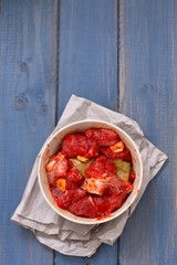 marinated meat in bowl on blue background
