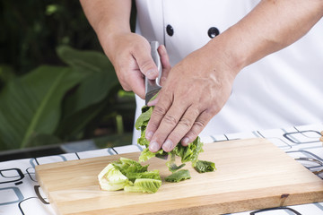 Chef holding slice lettuce on knife