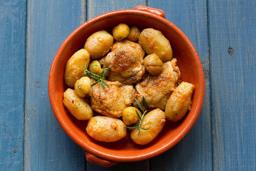 chicken with potato and chestnuts on ceramic dish on blue background