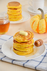 Pumpkin pancakes on white plate with butter and honey
