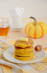 Pumpkin pancakes on white plate with butter and honey