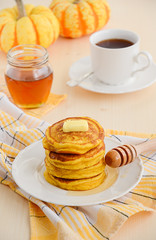 Pumpkin pancakes on white plate with butter and honey