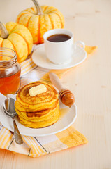 Pumpkin pancakes on white plate with butter and honey