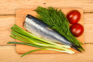 Herring double fillet with vegetables on wooden table