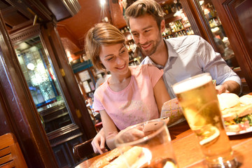 Couple of tourists in restaurant looking at map and smartphone
