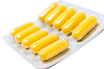 yellow pills in blister pack closeup on white background