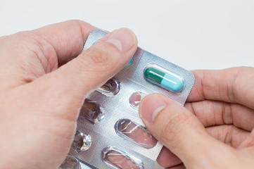 Close up of man's hand taking out pills from blister pack