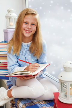 Adorable little girl, writing letter to Santa, sitting on a wind