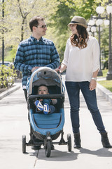 young family with baby strollers on city walk