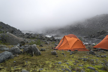 two orange tents on the foggy morning in mountains