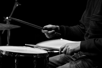Hands of a man playing a drum kit in black and white 