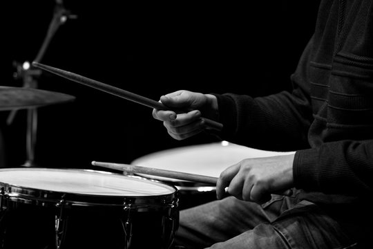 Hands of a man playing a drum kit in black and white 