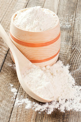 Flour in a wooden bowl on the table closeup