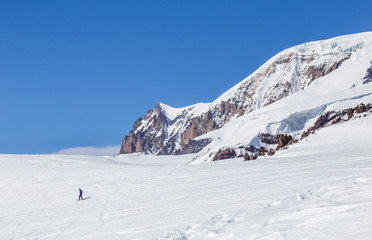 Lonely snowboarder riding near the mountain rocks