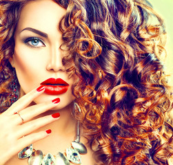 Beauty young brunette woman with curly hair, perfect makeup and manicure
