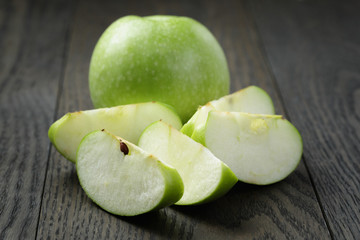 ripe green apples sliced on wood table