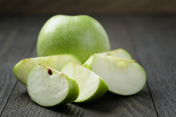 ripe green apples sliced on wood table