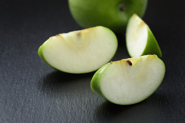 ripe green apples sliced on slate board
