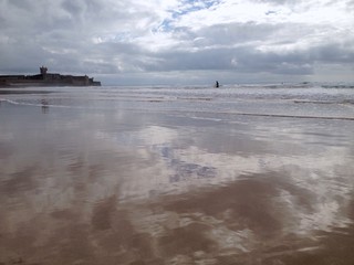 serene ocean with sky reflection and a surfer in waves