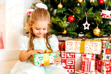 Obraz na płótnie Canvas Girl unwraps a gift. Christmas celebration