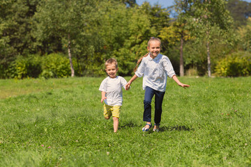 Fototapeta premium Children running on the grass in the park. Brother and sister. Image retro vintage filter effect. 