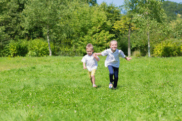 Obraz premium Happy brother and sister running on the grass