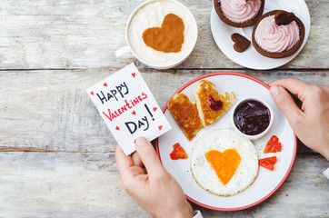 Men's hands hold a greeting card and a breakfast for Valentine's