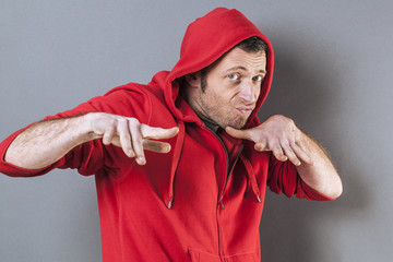 male adolescence concept - scared middle age wearing a red hooded sweater playing rapper with fun...