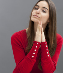 praying concept - bigoted 20s girl praying with both hands flat with pride and austerity for faith...