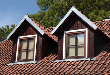 orange tiled roof and garret windows in old house - 95833489
